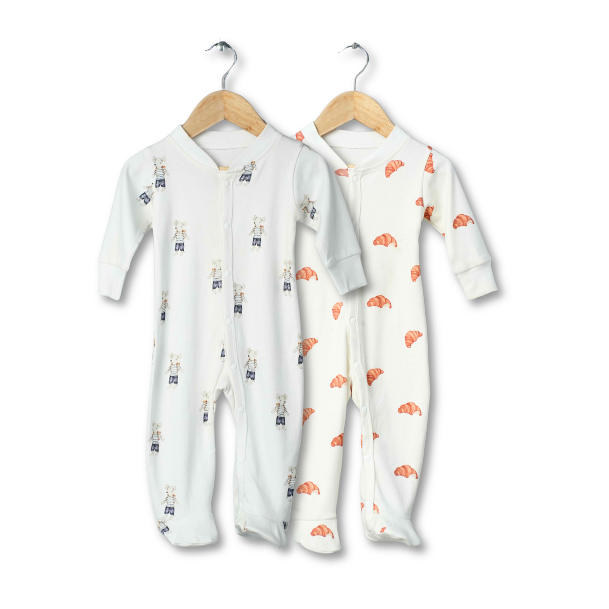 Two organic cotton footed onesies for babies, one in a long-sleeve style and the other in a sleeveless style, both with car patterns and stripes, displayed on hangers.