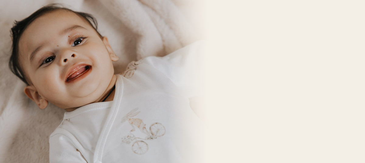 Smiling baby in a soft white organic cotton romper